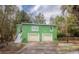 Bright green exterior featuring a two-car garage, staircase access, and surrounding mature trees at 1019 Prince St., Georgetown, SC 29440