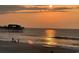A tranquil beach scene at sunset, featuring silhouettes of people and a pier reflected in the water at 115 Northbrook Dr, Murrells Inlet, SC 29576