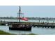 A pirate-themed tour boat navigates a waterway near a pier, with waterfront homes visible in the background at 115 Northbrook Dr, Murrells Inlet, SC 29576