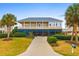 Inviting raised beach house with well-kept lawn, mature landscaping, and spacious covered parking at 1257 Ocean Blvd., Holden Beach, NC 28462