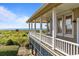 Spacious covered porch with ocean view and white railings, perfect for relaxing and enjoying the scenery at 1257 Ocean Blvd., Holden Beach, NC 28462