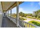 Expansive porch featuring white columns, railings, wood flooring, and serene views of the surrounding landscape at 1257 Ocean Blvd., Holden Beach, NC 28462