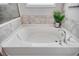 Large, luxurious soaking tub with tile surround, modern fixtures, and a decorative plant for a spa-like experience at 1439 Castleberry Pl., Myrtle Beach, SC 29588