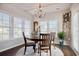 Sunlit dining room with a round wood table set beneath a chandelier, surrounded by large windows and stylish decor at 1439 Castleberry Pl., Myrtle Beach, SC 29588