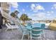 A backyard with a pool, palm trees, outdoor dining table, and lounge chairs under a bright, cloudy sky at 414 S Dogwood Dr., Garden City Beach, SC 29576