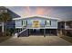 Charming coastal home with a blue exterior, black shutters, and a spacious drive-under garage at 414 S Dogwood Dr., Garden City Beach, SC 29576