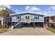 Charming coastal home with a blue exterior, black shutters, and a spacious drive-under garage at 414 S Dogwood Dr., Garden City Beach, SC 29576