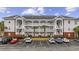Multi-story condo building with private balconies, palm trees, and ample parking at 4142 Hibiscus Dr. # 104, Little River, SC 29566