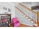 Cozy space under the staircase featuring wood flooring, pink recliner, bookshelf and white and wood staircase at 450 Deer Spring Loop, Georgetown, SC 29440