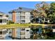Water view of condo building with blue siding, green lawn, three floors of screened in porch and lush foliage at 4637 Lightkeepers Way # 4-A, Little River, SC 29566