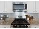 Close-up of the stainless-steel stove top and microwave, plus a decorative backsplash at 5064 Wavering Place Loop, Myrtle Beach, SC 29579