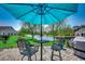 Seating area under a large blue umbrella provides a relaxing view of the yard, pond, and surrounding community at 808 Yauhannah Dr., Little River, SC 29566