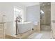 Bright bathroom featuring a soaking tub, glass shower, and marble-patterned accent wall at 1012 Dowitcher Dr., Conway, SC 29526