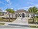 Stucco home featuring an arched double-door entryway, brick drive, meticulous landscaping, and palm trees at 1012 Dowitcher Dr., Conway, SC 29526