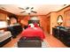 Cozy bedroom featuring a black headboard, red bedding, and wood-paneled walls at 1993 Meadowood Ln., Longs, SC 29568