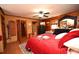 Bedroom featuring a black dresser, red bedding, wood-paneled walls, and a ceiling fan at 1993 Meadowood Ln., Longs, SC 29568