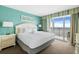 Bright bedroom with a queen bed and an ocean view through the sliding glass door at 2000 N Ocean Blvd. # 1601, Myrtle Beach, SC 29577