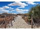 Picturesque sandy path to the beach, bordered by wooden posts, rope railings, and lush vegetation at 2405 S Ocean Blvd. # 105, North Myrtle Beach, SC 29582