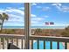 Balcony view of the ocean and pool, framed by railings and lush greenery at 2405 S Ocean Blvd. # 105, North Myrtle Beach, SC 29582