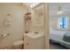 Bright bathroom with a white vanity, toilet, and view into the bedroom with ceiling fan at 301 N Waccamaw Dr. # 209, Garden City Beach, SC 29576