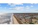 Wide aerial view of a coastline featuring a sandy beach, oceanfront buildings, and a residential area under a partly cloudy blue sky at 310 37Th Ave. N, North Myrtle Beach, SC 29582