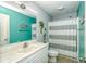 Coastal-themed bathroom with a turquoise accent wall, framed mirror, and a modern vanity and shower at 6001 - 1527 S Kings Hwy., Myrtle Beach, SC 29575