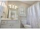 White bathroom features a white vanity and toilet, mirror, paisley patterned shower curtain, and window with blinds at 703 37Th Ave. S, North Myrtle Beach, SC 29582