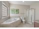 Bright primary bathroom featuring a corner tub with tile surround, glass shower, toilet, and a window with privacy glass at 703 37Th Ave. S, North Myrtle Beach, SC 29582