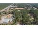 An aerial view features a residence and warehouse among green trees at 77 Towhee St., Georgetown, SC 29440