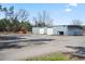 Wide shot of the metal commercial building with two garage doors, a rural setting, and a blue sky at 77 Towhee St., Georgetown, SC 29440