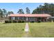 Charming brick home with a metal roof, a well-manicured lawn, and mature landscaping at 77 Towhee St., Georgetown, SC 29440