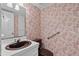 Bathroom showcasing a patterned wall, a toilet with a safety bar, and a vanity with a brown sink at 5616 N Kings Hwy., Myrtle Beach, SC 29577