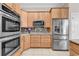 Modern kitchen with stainless steel appliances and stone backsplash against wood cabinetry at 129 Waterfall Circle, Little River, SC 29566