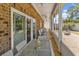 Covered patio with brick facade, glass doors, white wicker furniture and backyard view at 129 Waterfall Circle, Little River, SC 29566