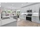 Bright kitchen with white cabinets, stainless steel appliances, an island with bar seating, and light hardwood floors at 870 Monterrosa Dr., Myrtle Beach, SC 29572