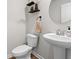 Well-lit half bathroom featuring pedestal sink, round mirror, and decorative shelving at 380 Harvest Ridge Way, Conway, SC 29527