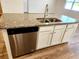 Kitchen island boasts granite countertops, a stainless steel dishwasher and a double sink with modern faucet at 5088 Wavering Place Loop, Myrtle Beach, SC 29579