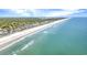 An aerial view highlighting beachfront homes along the shore with crystal clear blue water and a sandy beach at 100 Deloach Trail, Pawleys Island, SC 29585