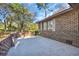 Brick home featuring a small concrete patio and brick privacy wall overlooking a wooded yard at 100 Deloach Trail, Pawleys Island, SC 29585