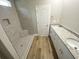 Bathroom featuring a tiled shower, double sink vanity with granite countertops, and stylish wood-look flooring at 311 St. Andrews Ln., Myrtle Beach, SC 29588