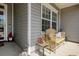 Covered front porch with wooden bench, side table, and charming decorations near the front door at 321 Galway Ct., Longs, SC 29568