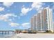 An exterior view of a condo building and pier with a beautiful beach in the foreground at 3500 N Ocean Blvd. # 902, North Myrtle Beach, SC 29582