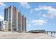 Exterior view of condo building near a sandy beach and pier on a bright, sunny day at 3500 N Ocean Blvd. # 902, North Myrtle Beach, SC 29582