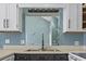 Close-up of kitchen features a sink with faucet, mirror, and white cabinets at 3700 Golf Colony Lane # 13-H, Little River, SC 29566