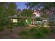 Charming home with a vibrant turquoise door, lush landscaping, and warm, inviting lighting at 404 66Th Ave. N, Myrtle Beach, SC 29572