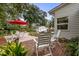 Outdoor patio with brick flooring, white seating, red umbrella, and lush greenery at 404 66Th Ave. N, Myrtle Beach, SC 29572