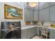 Well-lit laundry room featuring gray cabinets, desk space, marble counters, and designer chandelier at 404 Club Dr., Myrtle Beach, SC 29572
