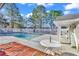 Community pool with a white fence, surrounded by pine trees, and a table with chairs at 4814 Innisbrook Ct. # 412, Myrtle Beach, SC 29579