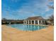 Community pool with adjacent clubhouse, featuring ample seating and shaded areas under a sunny, partly cloudy sky at 511 Mattamushkeet Dr., Little River, SC 29566