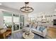Open-concept living room featuring a modern chandelier, a plush sofa, and sliding glass doors to the deck at 512 9Th Ave. S, North Myrtle Beach, SC 29582